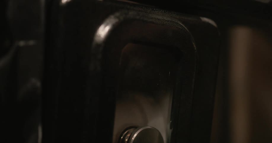 Hand opening a door of an old movie camera