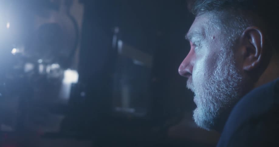 A man looks inside a working film projector then nods and closes it