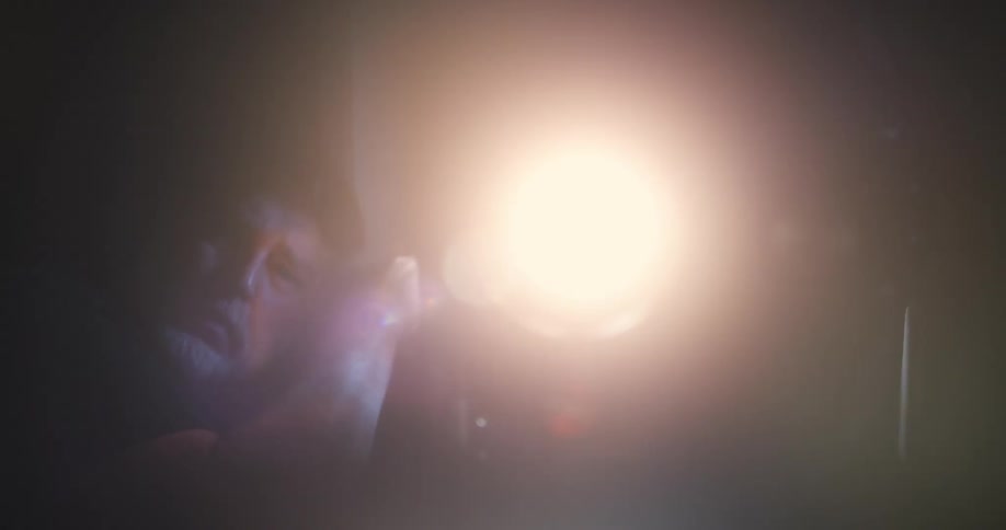 The face of a man holding a flashlight with a strong light and then it turns off