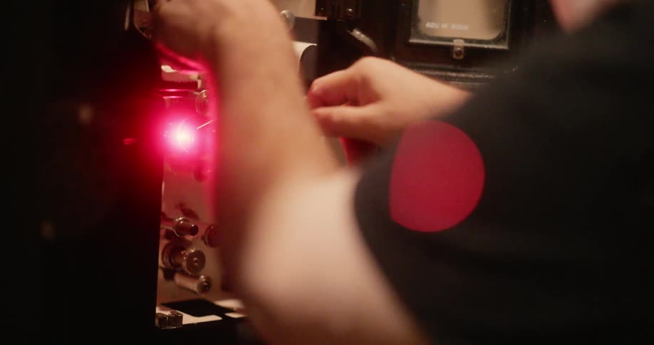 Hands adjusting a film on a cinema projector