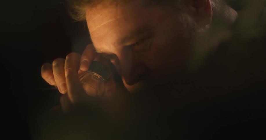 Concentrated man looking at an object while standing in a dark room