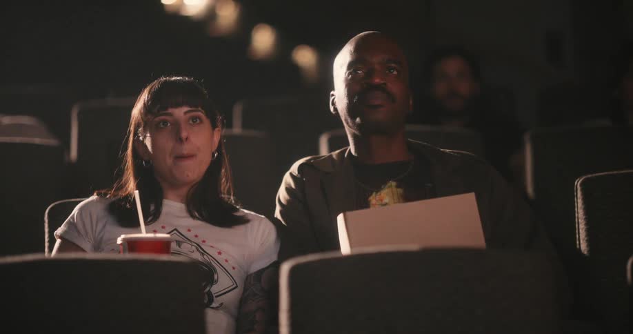 Couple on a movie date eat popcorn and sip a drink