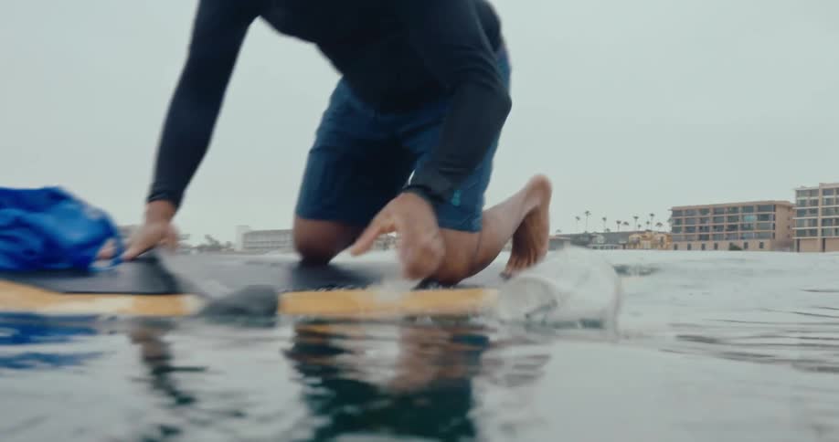 Man balancing on a surfboard in the sea and collecting floating trash
