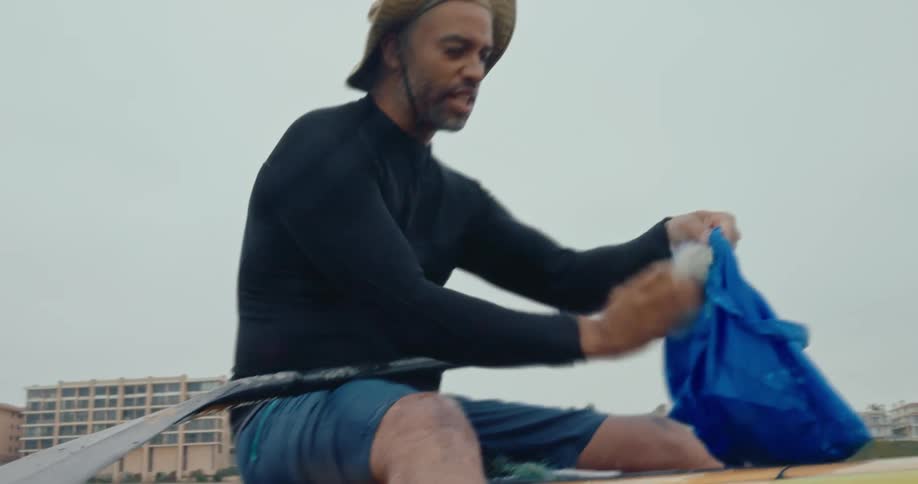 Man floating with kayak in the sea and removing garbage from the water