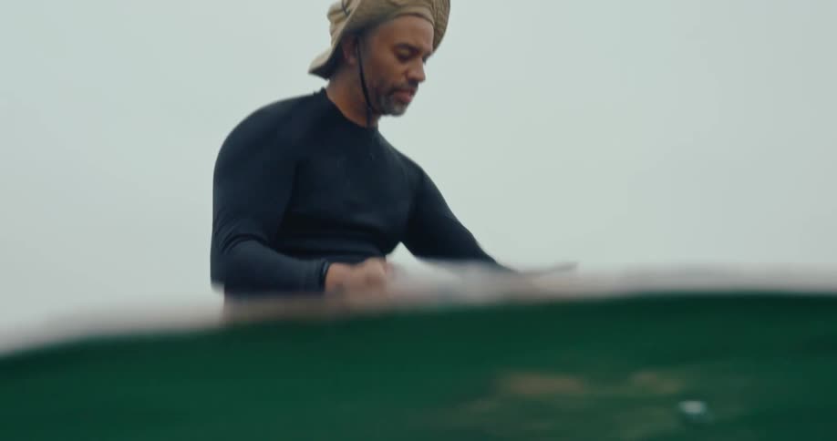 Man sitting on a paddle board rinses a plastic object and puts it in a bag