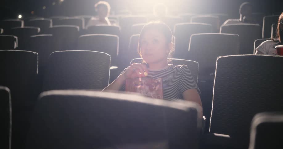 People sitting in a movie theater eating popcorn