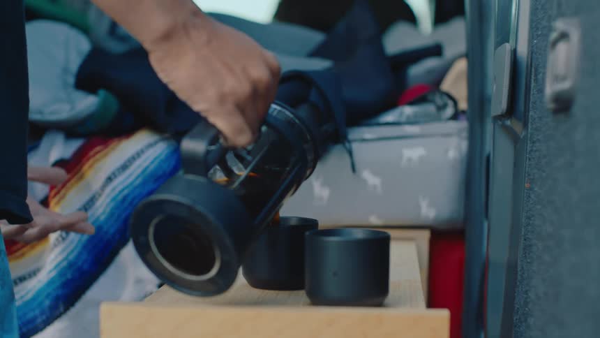 Man in large traveling vehicle pours coffee into a couple of cups