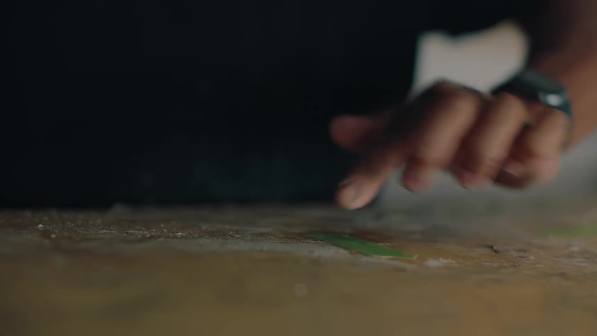 Man jumping over pieces of green tape on top of a plank surface