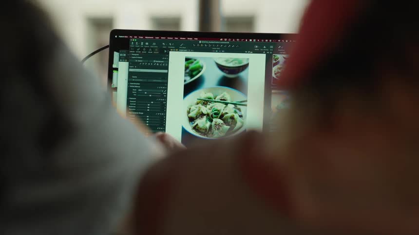 Two women collaborate while reviewing photographs on a computer