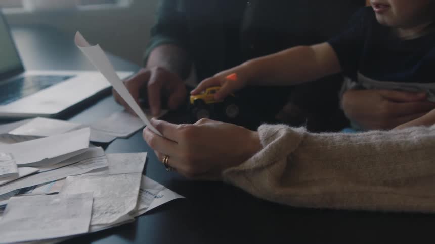 Son plays with a toy while his parents work on their finances