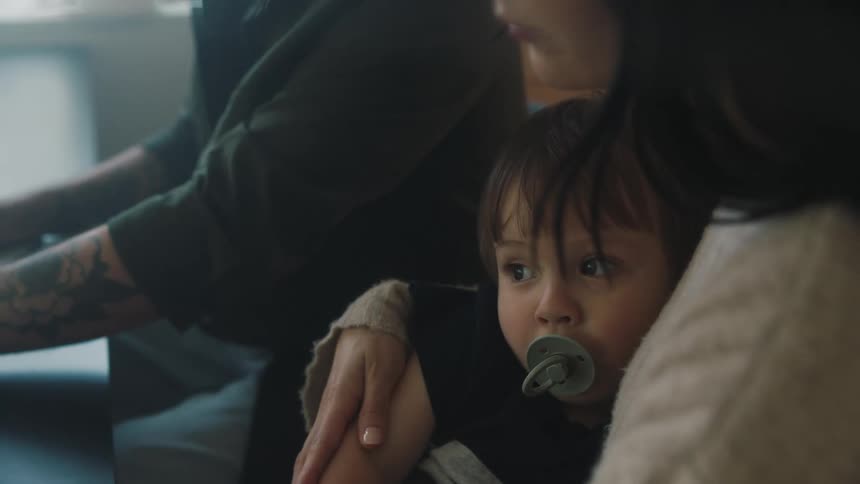 Mother holds her toddler while sitting at a table with the father