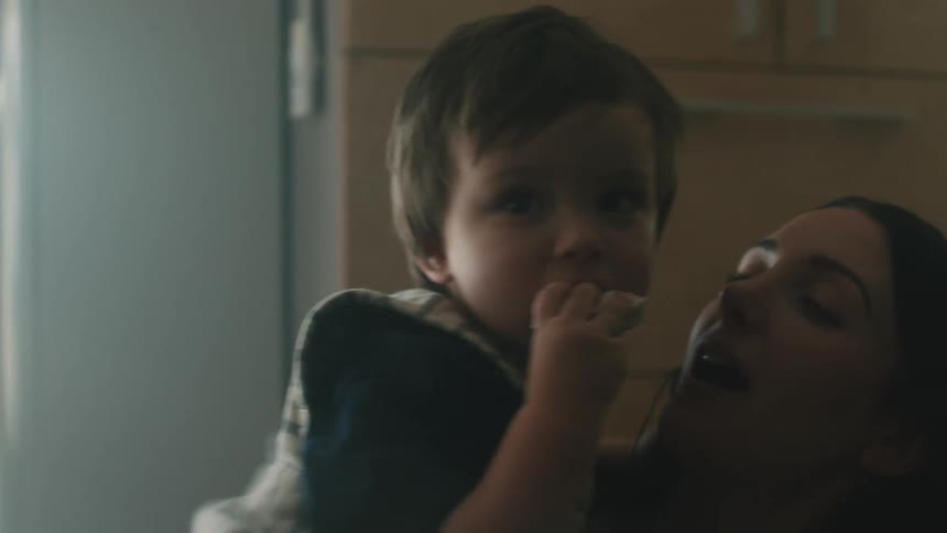A mother cradles her son in her arms as he enjoys a cookie at home