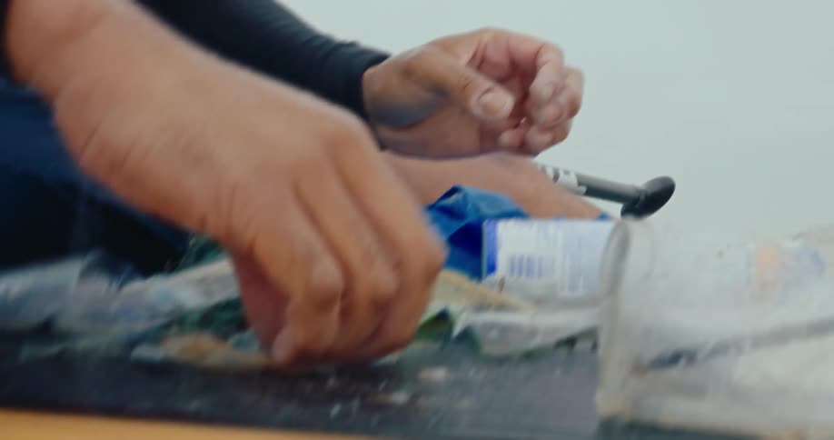 A man is sorting through trash he grabbed from the ocean