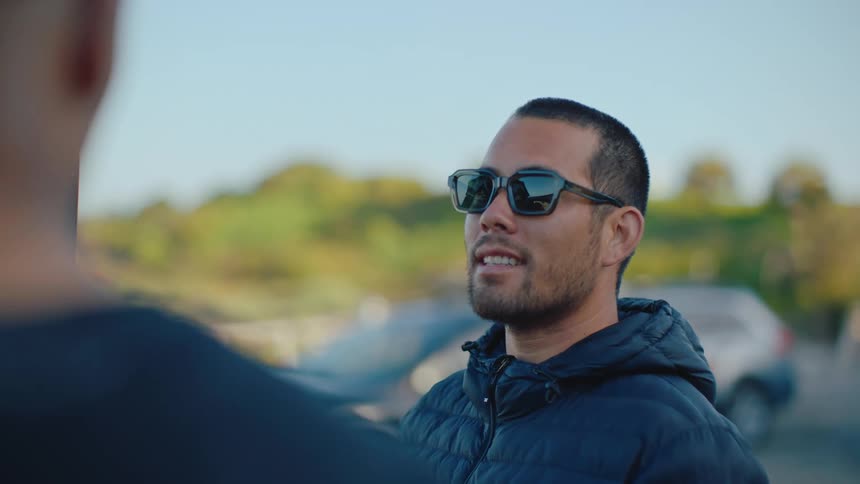 Man with sunglasses talking to a person next to him