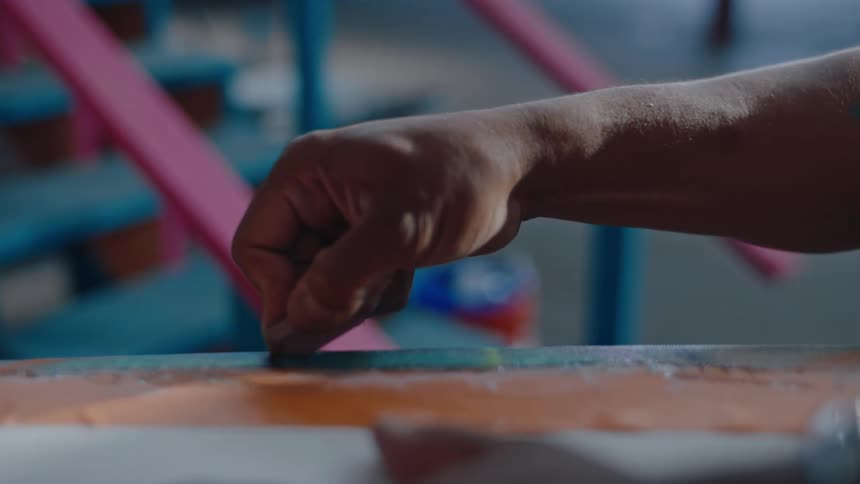 Man scores a surfboard with a razor while working in the workshop