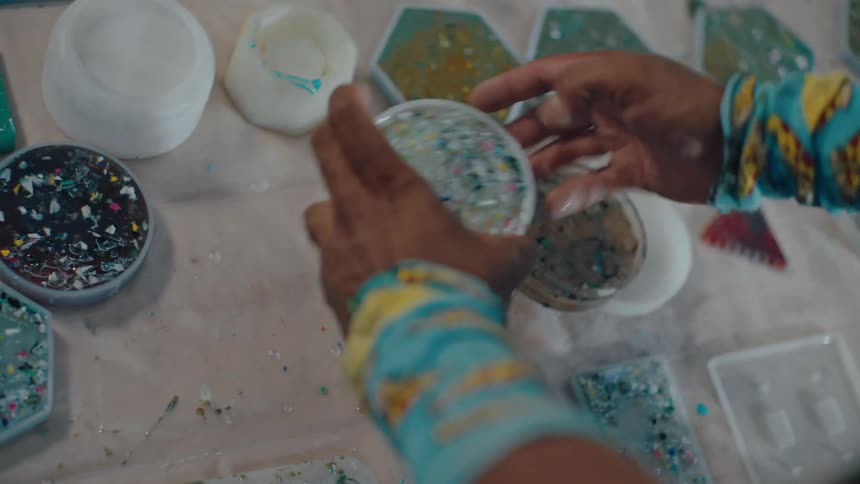 Pair of hands removing a round recyclable silicone object from a table