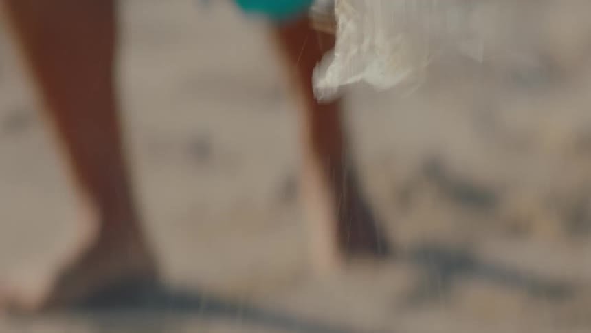 Tool collecting trash on the beach sand by a person