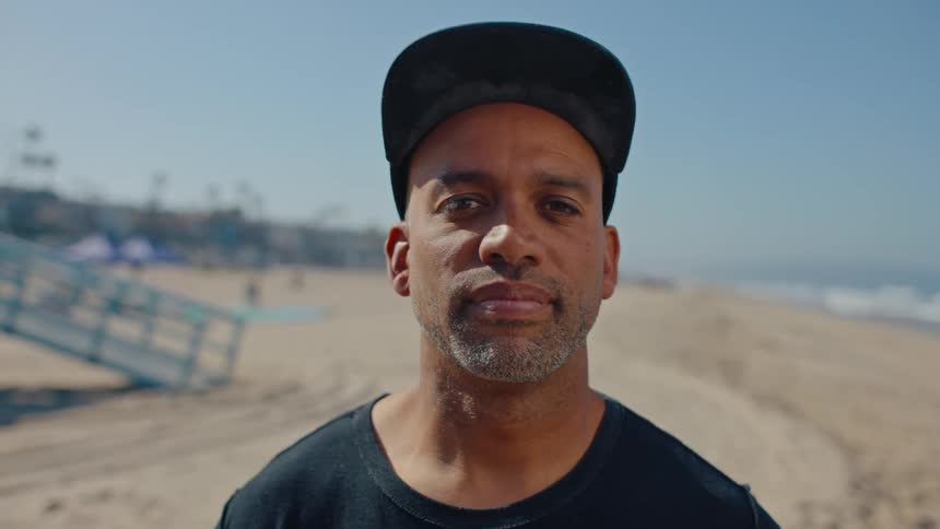 Portrait of a man wearing a cap and standing on the sand at the beach
