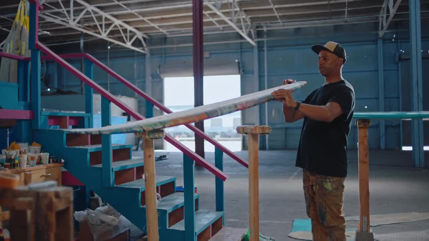 Man placing a surfboard on top of a wooden surface