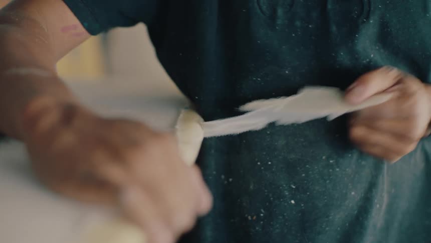 A person tears the coating of a surfboard using their hands