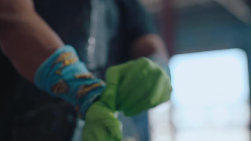 Pair of hands putting on green disposable gloves