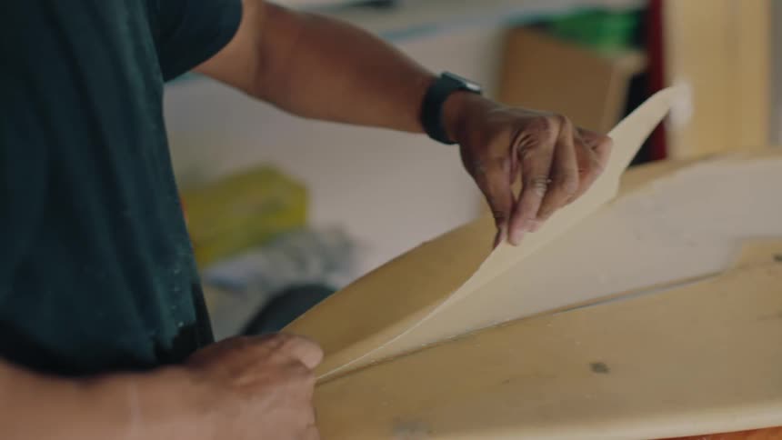 A person cutting a surface of a board and removing a piece
