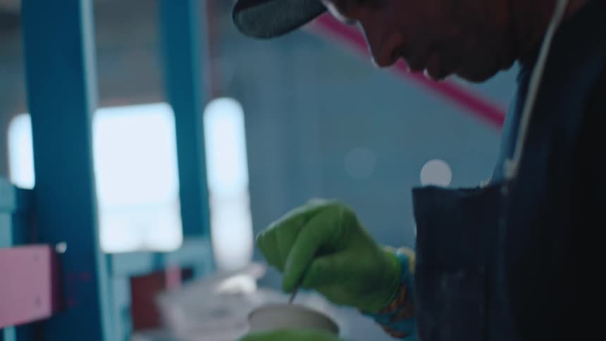 Man mixing paint in a cup in a blue room