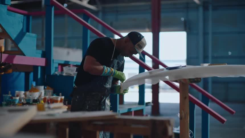 A man mixes paint to apply on a surfboard