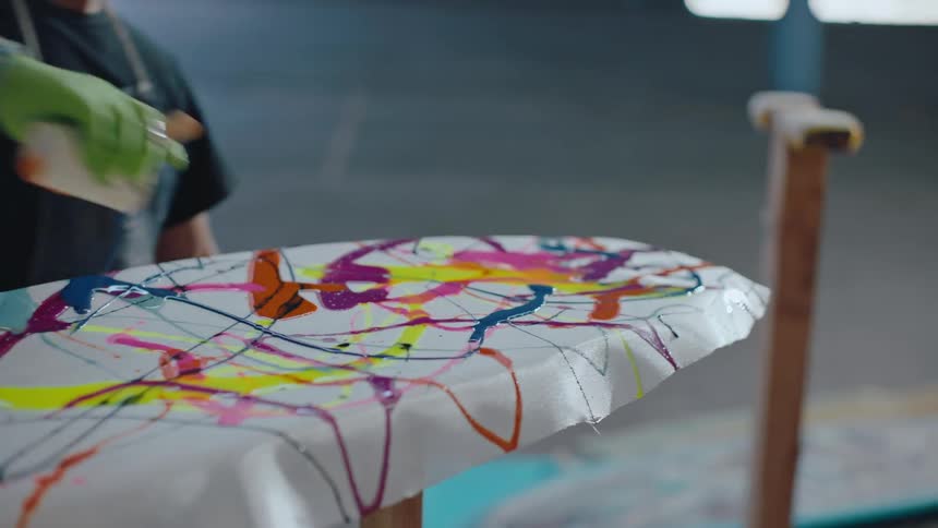 A person dropping some colorful colors on a surface of a white sheet