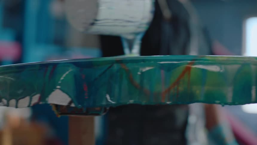 A person is throwing blue paint on a plank that is resting on a piece of wood