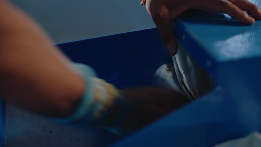 Hand throwing trash and recycling into a blue container