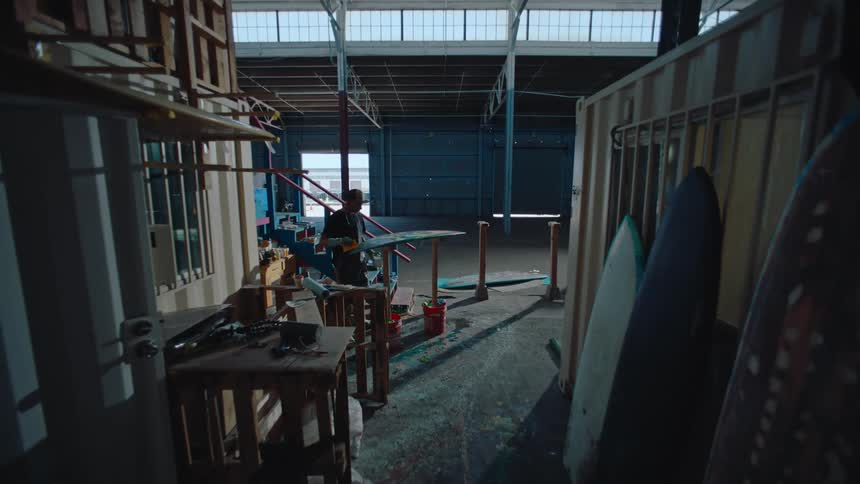 Man working on a surfboard in a shed
