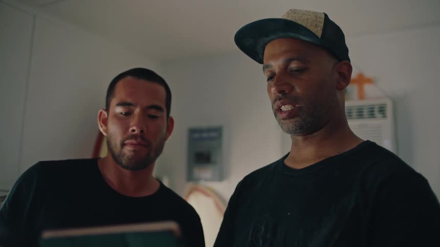 Portrait of two men talking side by side and one of them holding a tablet