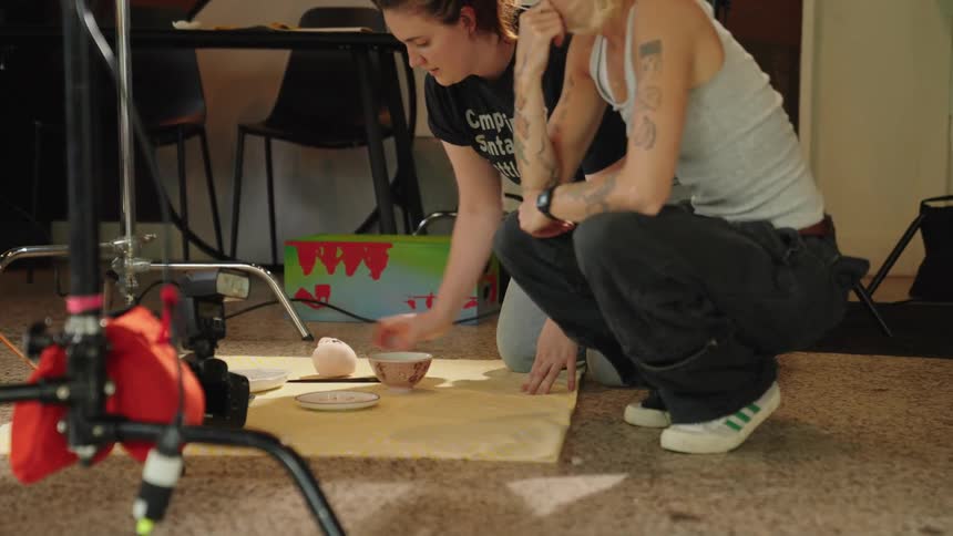 Two women in a photography setting setting up a scene with plates of food
