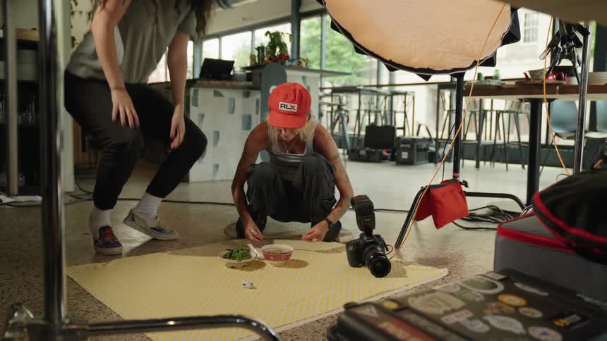 Two women preparing a scene with two bowls in an indoor environment with professional camera equipment