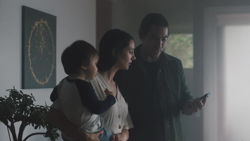 Father using smartphone next to mother holding a small boy