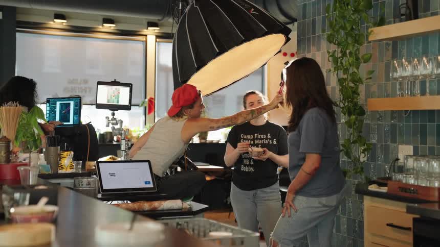 A behindthescenes production set with a photographer cameras and lighting equipment on a restaurant