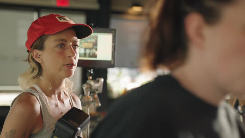 Two women talk on a photo shoot set in a restaurant