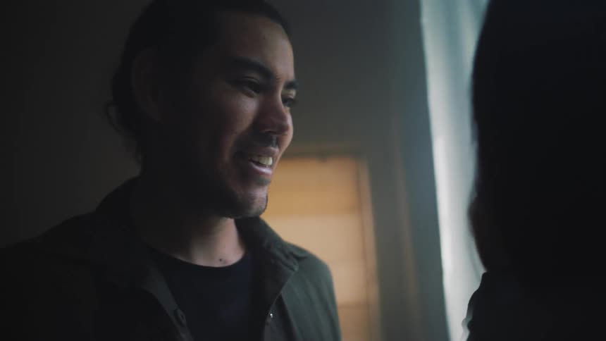 A man is talking and smiling with someone who is in front of him and holding a baby