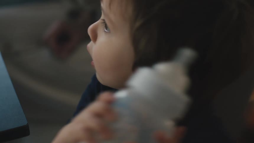 A little boy holding a bottle and shaking it up and down