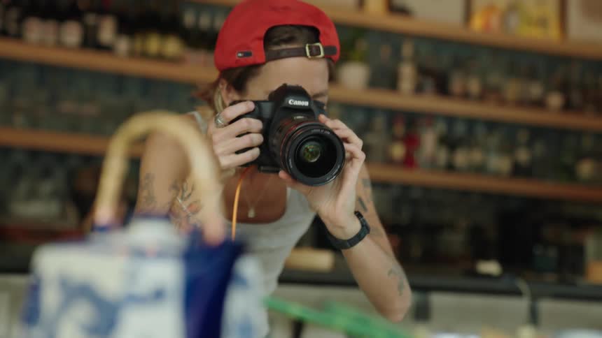 A photographer uses a camera to take pictures of food in a restaurant