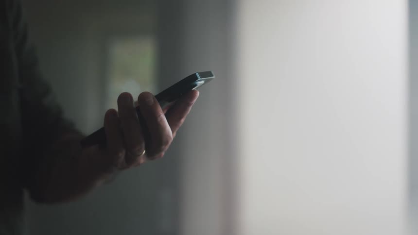 A pair of hands holding a smartphone fingers tapping on the screen