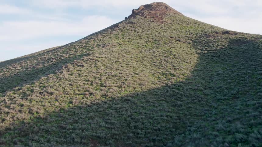 Ascending along the steep slope of a shrub and brush covered hillside
