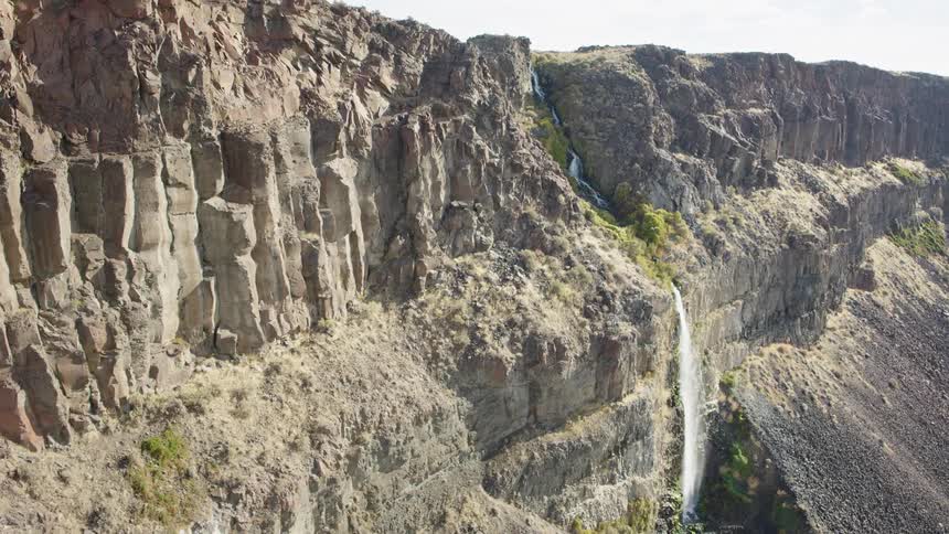 Subtle orbit around a sheer rock wall with a beautiful waterfall streaming down the center