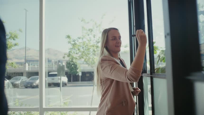 A woman smiles writing something on a window