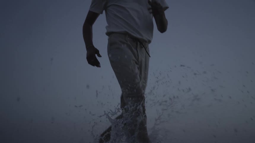 Man running in water on a cloudy day