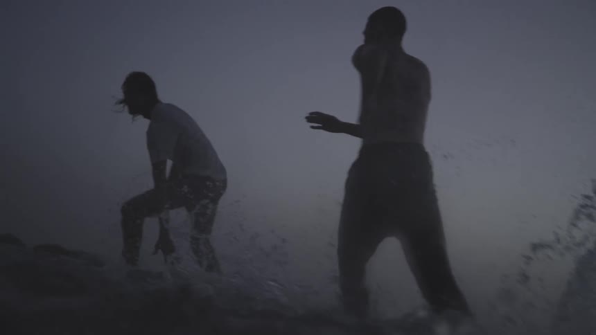 Silhouette of two people running playing in the water