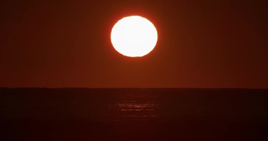 Sea landscape with sun rising on the horizon in a reddish sky