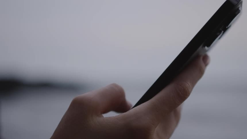 Closeup of a persons hand scrolling on a smartphone