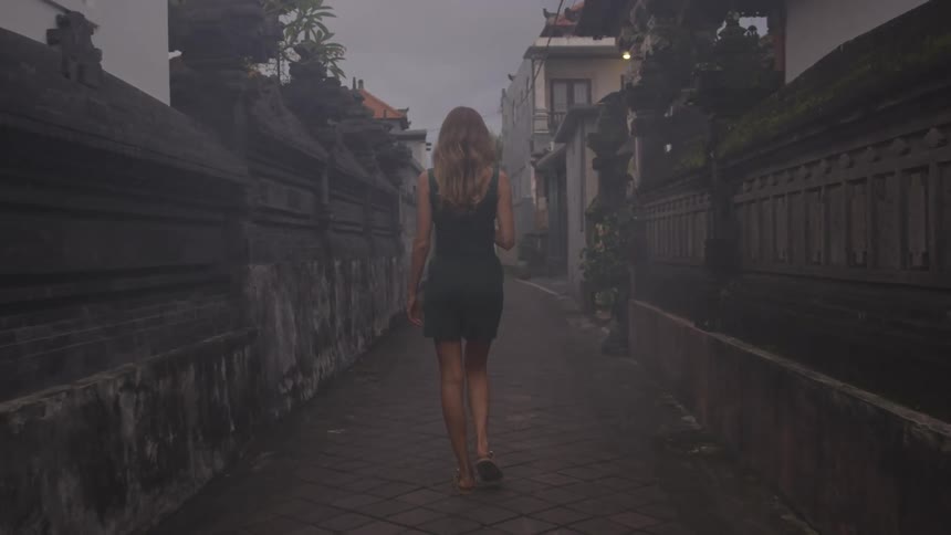 Woman in a short dress walking on a narrow street in a residential neighborhood